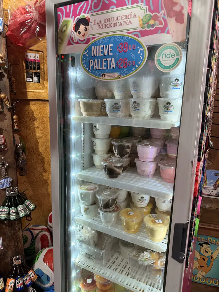 Congelador con paletas y botes de nieve bajo el letrero La Dulcería Mexicana Nieve y Paleta